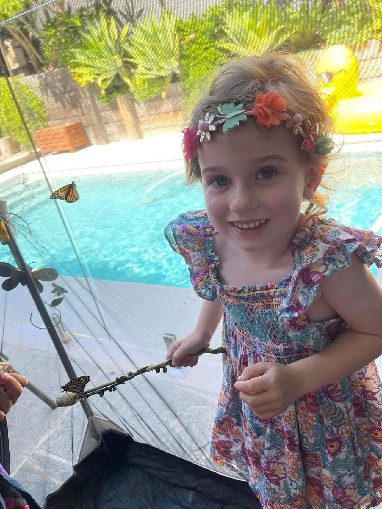 Girl smiling with a monarch butterfly on a wand
